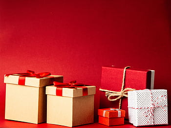 A collection of colorful gift boxes with ribbons on a rich red background, perfect for holiday themes. HD wallpaper