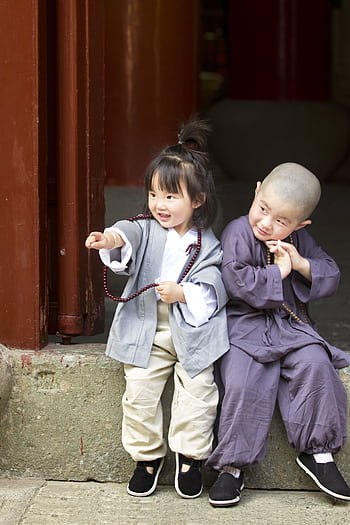Two children in traditional monk attire share a joyful moment outdoors. HD phone wallpaper