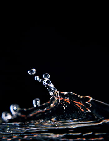 Capture of a water splash in mid-air against a dark background, emphasizing motion and clarity. HD phone wallpaper
