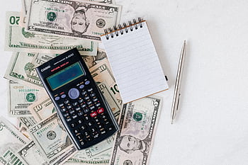 Flat lay of US dollar bills with calculator and notebook for budgeting. HD wallpaper