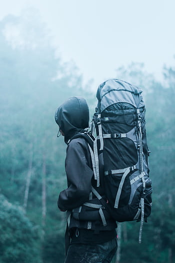 Solo hiker with large backpack in a misty forest, exploring nature's serene beauty. HD phone wallpaper