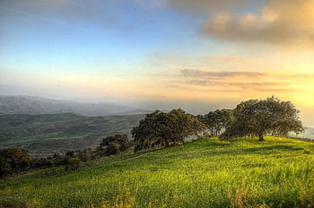Breathtaking sunrise landscape with serene hills and lush greenery under a vibrant sky. HD wallpaper