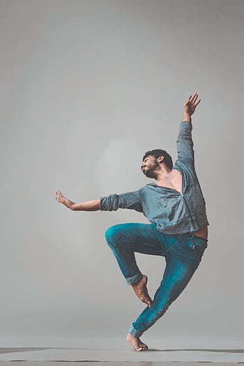 A male dancer strikes a dynamic pose in a studio setting, showcasing contemporary dance style. HD phone wallpaper