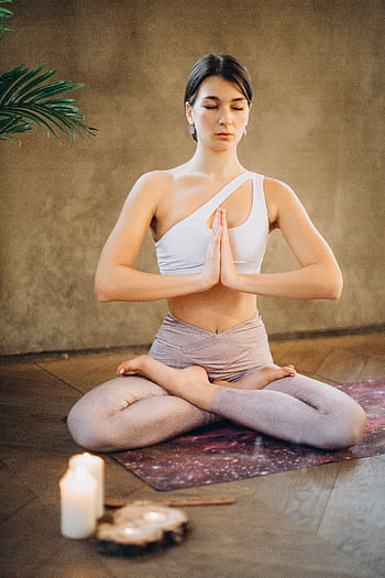 A woman meditating in a lotus pose with candles in a tranquil indoor setting. HD phone wallpaper