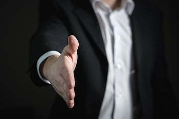 Close-up of a businessman extending hand for a handshake, symbolizing agreement and partnership. HD wallpaper