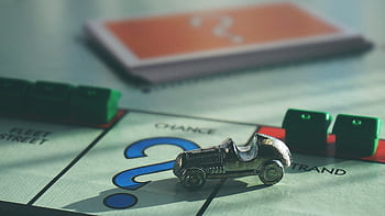 A close-up of a Monopoly board game featuring a silver car token and chance card. HD wallpaper