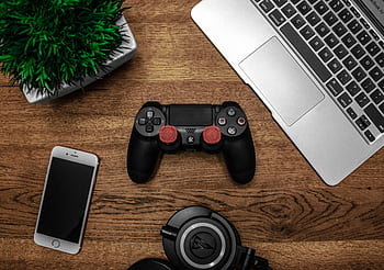 A flat lay showcasing a gaming console, laptop, smart, and heads on a wooden tabletop. HD wallpaper