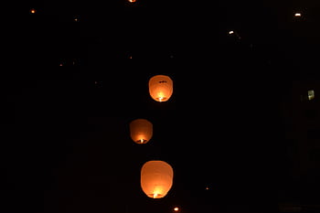 Sky lanterns glowing warmly as they ascend into the night sky. HD wallpaper