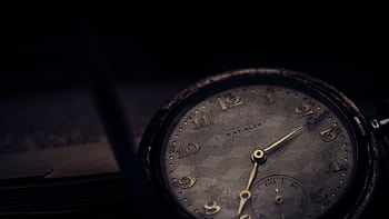 Close-up of a vintage pocket watch with a textured dial in a moody setting. HD wallpaper