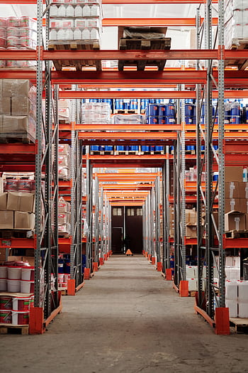 A modern warehouse interior showcasing organized shelves and pallets for efficient storage. HD phone wallpaper