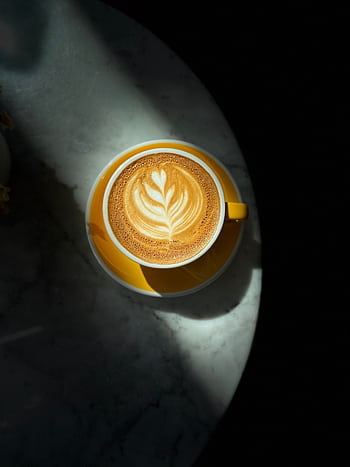 Top view of a beautifully crafted latte with art on a marble table under dramatic lighting. HD phone wallpaper