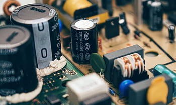 Detailed close-up of capacitors and components on a circuit board, showcasing electronic technology. HD wallpaper