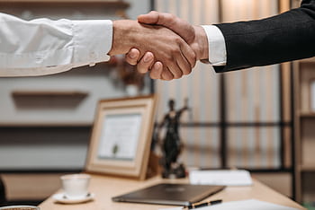 Close-up of a handshake between two professionals in a modern office setting, emphasizing partnership and agreement. HD wallpaper