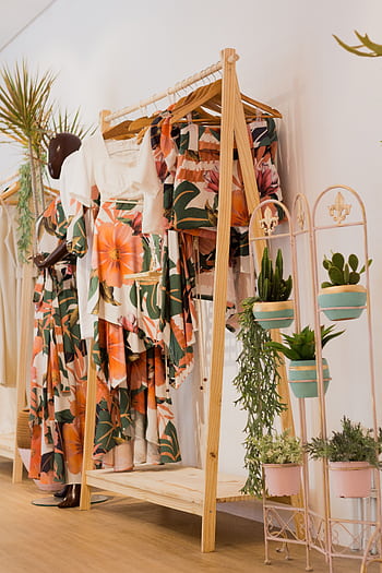 Floral print clothing elegantly displayed in a modern boutique with lush green plants for decoration. HD phone wallpaper