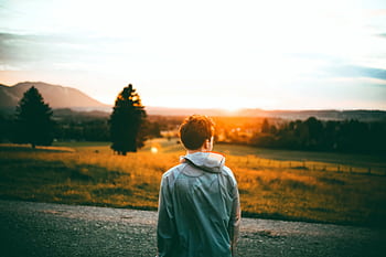 A young man enjoys a serene sunset view in Ohlstadt, Germany, surrounded by nature. HD wallpaper