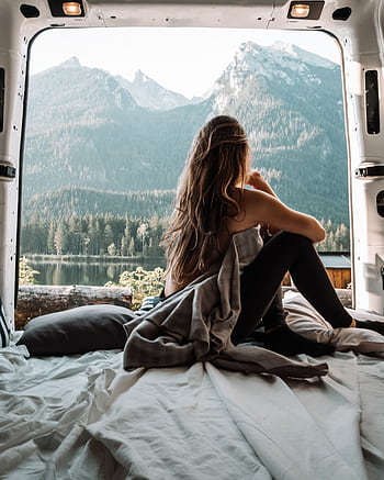 A woman enjoying a peaceful moment inside a campervan with a stunning mountain view, embracing the van life and nature. HD phone wallpaper
