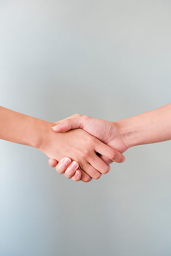 A detailed view of a handshake between two individuals, symbolizing agreement and collaboration. HD phone wallpaper