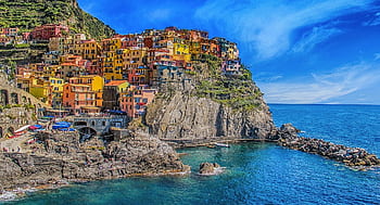 Vivid view of Manarola's colorful houses perched on cliffs, overlooking the blue sea. HD wallpaper