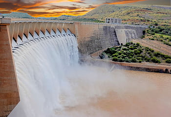 Scenic view of a large dam with cascading water and dramatic sunset skies. HD wallpaper