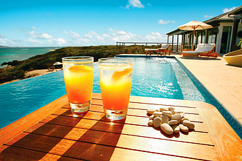Two colds drinks and a pile of rocks sitting next to a beachside pool, sand, luxury, coast, tropical, rocks, orange, drinks, beach, shore, fancy, pool, swimming pool, water, drink, ocean HD wallpaper