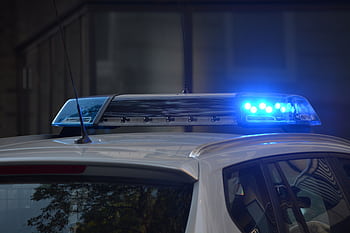 Close-up of a police car's flashing blue lights in an urban environment. HD wallpaper