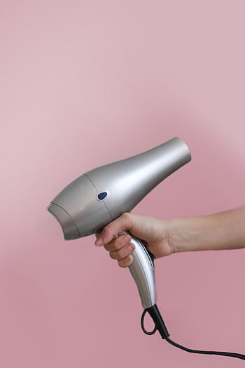 Close-up of a hand holding a silver hair dryer on a pink background. HD phone wallpaper