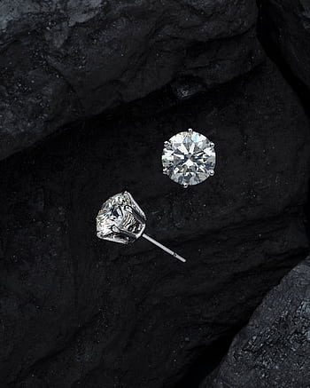 Close-up of luxury diamond earrings on textured black stone, showcasing elegance. HD phone wallpaper