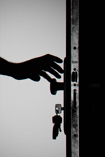 Silhouette of a hand about to open a door with keys in lock, symbolizing security. HD phone wallpaper