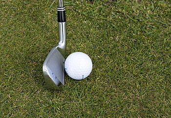 Golf club and ball on grass showcasing a leisure sport scene outdoors. HD wallpaper