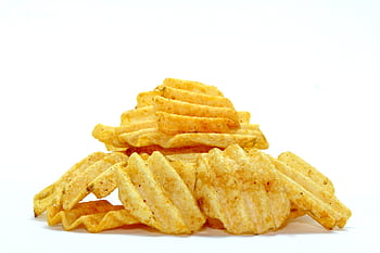 A close-up of crispy wavy potato chips stacked against a white background, highlighting their texture. HD wallpaper