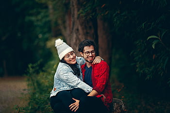 Happy couple sitting together in a green park, enjoying a joyful moment filled with love and affection. HD wallpaper