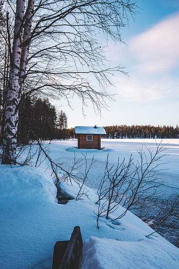 Scenic winter view of a frozen lake and wooden shed surrounded by snow in Jyväskylä, Finland. HD phone wallpaper