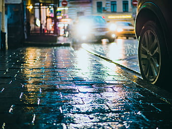 Long exposure of a wet city street with car headlights reflecting on pavement at night. HD wallpaper