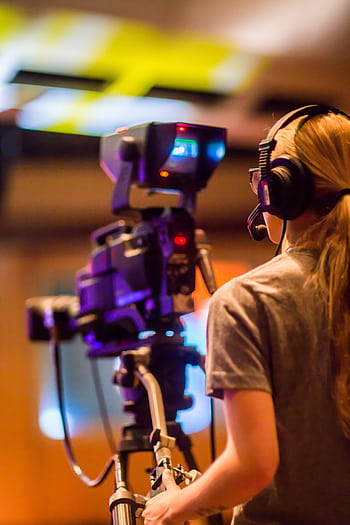 A woman operates a professional camera indoors, focusing on media production. HD phone wallpaper