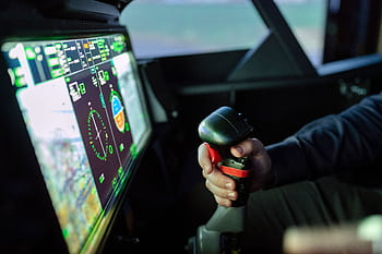 Close-up of a simulated aircraft cockpit with control joystick and digital display. HD wallpaper