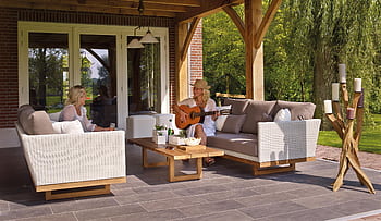 Two women enjoying a serene patio scene with a guitar and candles, surrounded by greenery. HD wallpaper