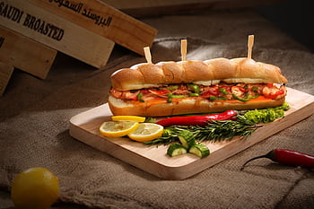 Mouth-watering sandwich with vegetables and sausage on wooden board, perfect for a delicious meal. HD wallpaper
