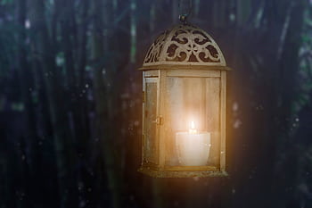 Warm glow of a candle inside a vintage lantern against a blurred dark background. HD wallpaper