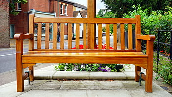 A wooden bench is placed in an urban street surrounded by vibrant flowers. HD wallpaper