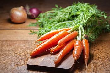 A bunch of fresh organic carrots on a wooden board, emphasizing healthy eating. HD wallpaper