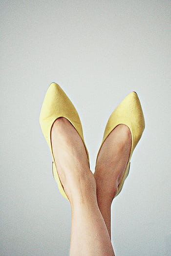 Elegant yellow pointed shoes worn by a woman with legs crossed against a plain background. HD phone wallpaper