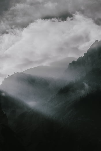A breathtaking panoramic view of a fog-covered mountain range with dramatic lighting and clouds. HD phone wallpaper
