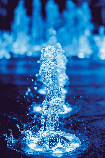A dynamic close-up of a water fountain splash captured in vivid blue tones, showcasing motion and liquid beauty. HD phone wallpaper