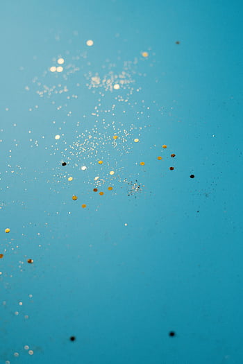 Enchanting vertical shot of gold glitter sparkles on a vibrant turquoise backdrop, perfect for artistic designs. HD phone wallpaper