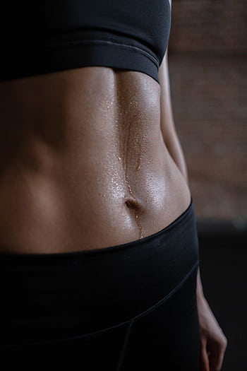A close-up of a fit woman's toned abdomen with sweat, emphasizing fitness and strength. HD phone wallpaper