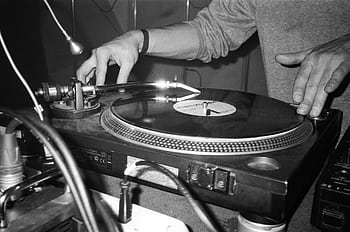 Close-up of a DJ using a turntable to play vinyl records, showcasing music equipment. HD wallpaper