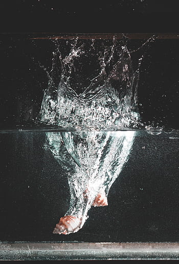 Capture of a seashell creating a dynamic splash underwater with visible bubbles. HD phone wallpaper