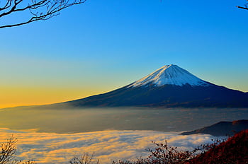Breathtaking view of Mount Fuji at sunrise, surrounded by misty clouds and vibrant sky. HD wallpaper