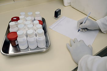 Laboratory technician writing report with samples in a medical lab. HD wallpaper