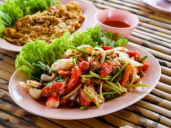 Authentic Thai seafood salad with fresh vegetables and herbs served on a pink plate. HD wallpaper